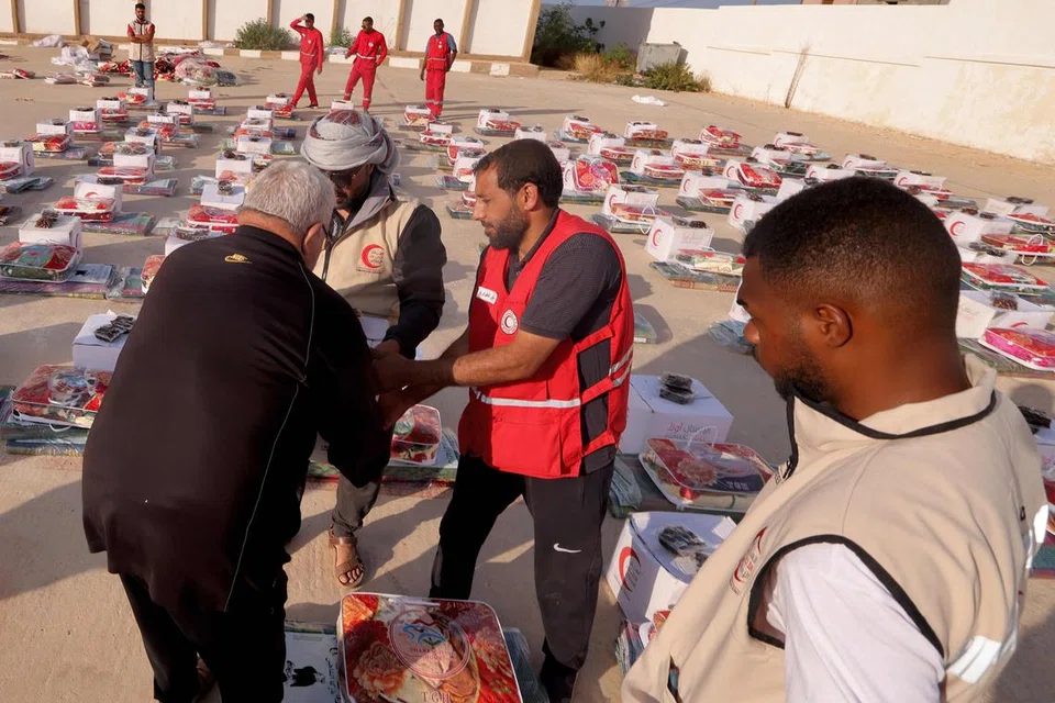 BANTUAN ANTARABANGSA: Para anggota Bulan Sabit Merah Amiriah Arab Bersatu (UAE) mengagihkan bantuan makanan kepada mangsa banjir di Derna pada Ahad.