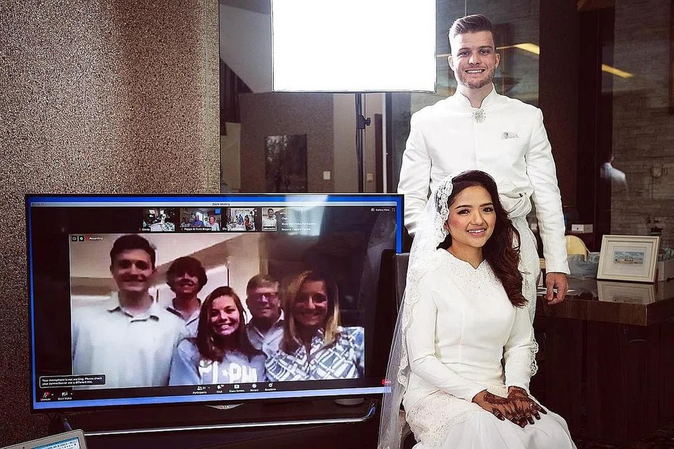 TEKNOLOGI RAPATKAN UKHUWAH WALAU JAUH: Farisha Ishak dan suami Encik Connor Cooke yang berasal dari North Carolina, Amerika, bernikah di Singapura baru-baru ini dengan keluarga Encik Cooke (dalam kaca televisyen) menyaksikan upacara akad nikah menerusi aplikasi Zoom.- Foto FANDY RAZAK