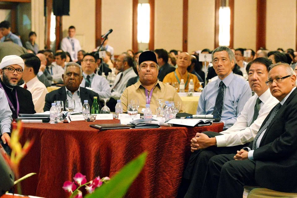 BERSAMA TENTANG PENGGANASAN: Encik Nathan (dua dari kiri) bersama Perdana Menteri, Encik Lee Hsien Loong (baju biru), dan Timbalan Perdana Menteri, Encik Teo Chee Hean (dua dari kanan), menyertai anggota Kumpulan Pemulihan Keagamaan (RRG) semasa sidang antarabangsa mengenai pemulihan pengganas anjuran Sekolah Pengajian Antarabangsa S. Rajaratnam (RSIS) dan RRG di Pusat Konvensyen Raffles pada 26 Mac 2013. - Foto-foto fail
