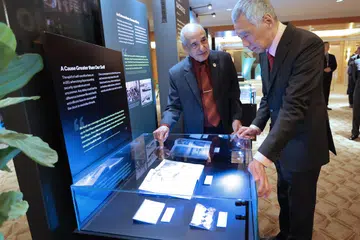 PAMERAN KES BERSEJARAH: Mantan pegawai Jabatan Keselamatan Dalam Negeri (ISD), Encik Saraj Din (kiri), memberi taklimat tentang kes lalu yang pernah diuruskan ISD kepada Perdana Menteri, Encik Lee Hsien Loong. Kes tersebut dipamerkan semasa acara jamuan malam tertutup sempena ulang tahun ke-75 ISD pada Selasa di The Ritz-Carlton, Millenia Singapore.
