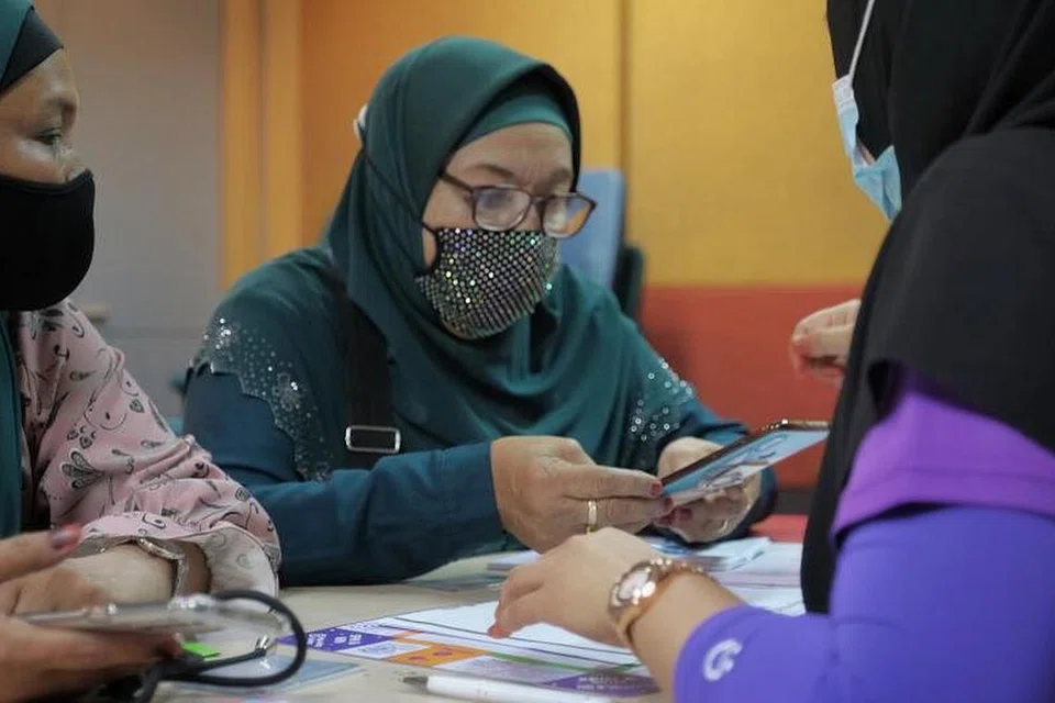 PELAJARI KEMAHIRAN DIGITAL: Cik Mahani Mohammed (berbaju hijau tua & gambar sisipan) menyertai progam Gerakan Transformasi Digital untuk Warga Emas di hab masyarakat SG Digital di Kelab Masyarakat Toa Payoh Central untuk mempelajari kemahiran digital. 