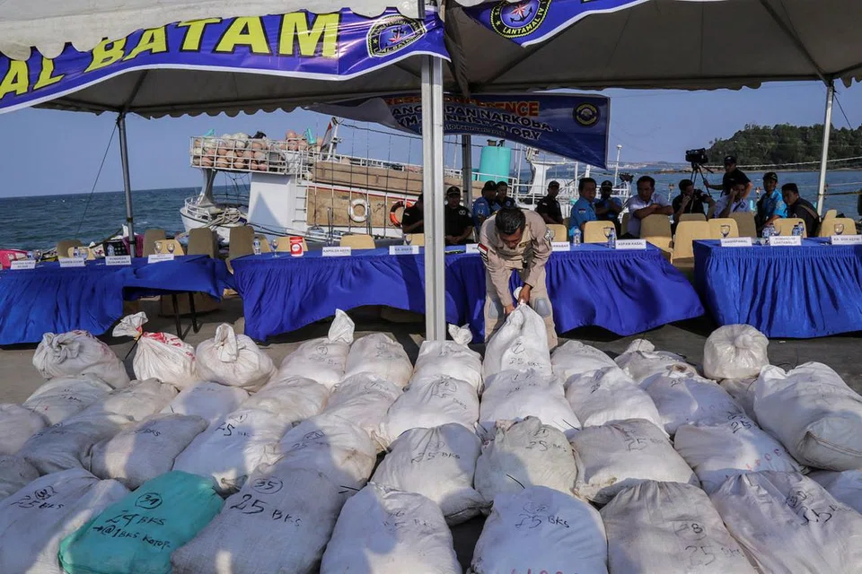 PERIKSA DADAH YANG DIRAMPAS: Pegawai angkatan laut Indonesia sedang memeriksa guni-guni beras yang mengandungi satu tan dadah methamphetamine kristal di Batam yang dirampas daripada sebuah kapal nelayan. - Foto REUTERS