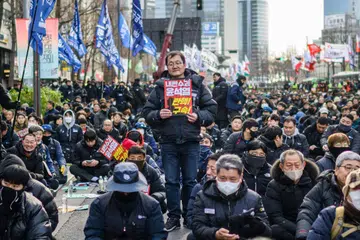 Encik Kim Sung-tae (tengah), seorang pekerja berusia 52 tahun di sebuah syarikat pengeluar alat ganti kereta, bergambar sambil memegang ‘placard’ bertulis, “Pengkhianat Yoon Suk Yeol. Dakwa! Tangkap!” ketika menyertai tunjuk perasaan kumpulan buruh yang mengadakan bantahan bagi mendesak pemecatan Presiden Korea Selatan, Yoon Suk Yeol, di hadapan Dewan Bandaraya Seoul pada 12 Disember. 