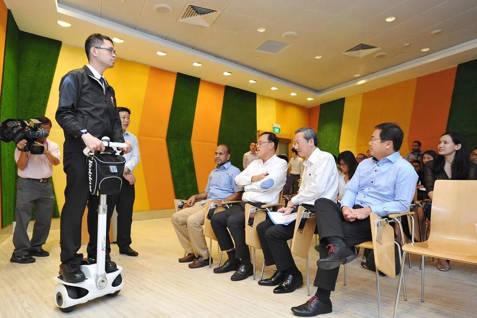 GUNA TEKNOLOGI: Encik Melvin Chong, pegawai keselamatan bersama Reachfield Security and Safety Management Pte Ltd, menunjukkan cara menggunakan segway kepada Encik Sam Tan (dua dari kanan). - Foto THE STRAITS TIMES