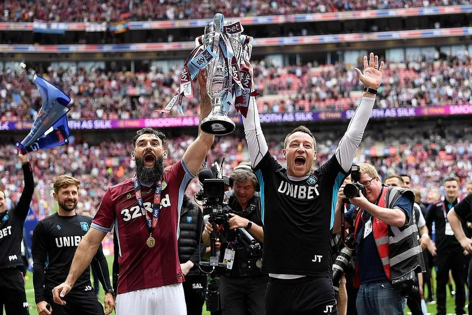 NAIK LIGA: Pemain Aston Villa, Mile Jedinak (kiri) dan penolong pengurus, John Terry, menyambut kemenangan mereka dengan trofi selepas menang dalam playoff. - Foto REUTERS