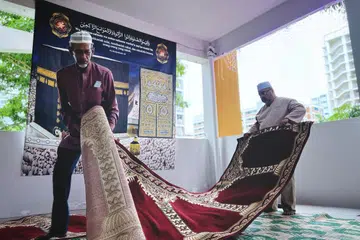Pengerusi Kariah Golden Pine, Encik Ibrahim Akbar (kanan) bersama bendahari jawatankuasa kariah tersebut, Encik Khamis Shukor, 69 tahun, kelihatan membentang sejadah di ruang kariah di Blok 827A Tampines Street 81.