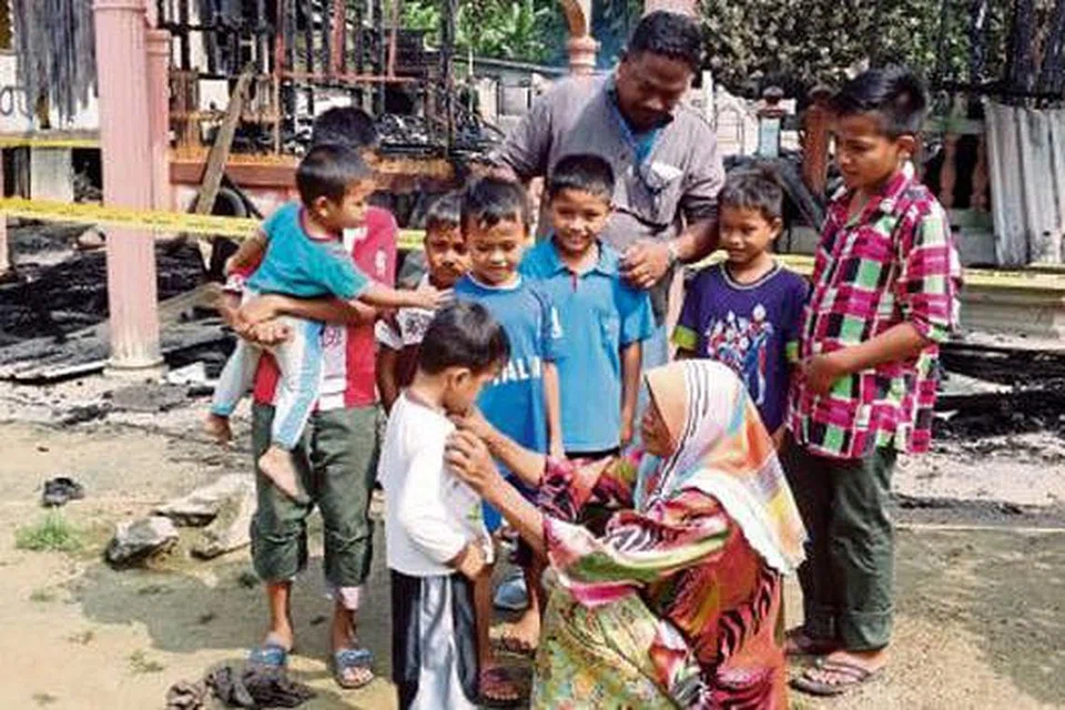 NENEK REDAH API: Cik Siti Bidah memperbetulkan baju cucunya selepas mereka tinggal sehelai sepinggang sebaik rumah yang didiami musnah terbakar di Kampung Tasik Pauh, Selising, Pasir Puteh. - Foto NSTP