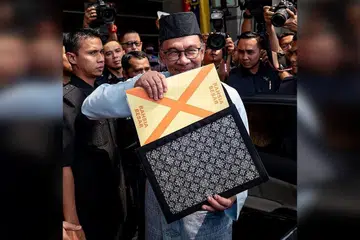 BENTANG BELANJAWAN: Datuk Seri Anwar yang berpakaian baju Melayu lengkap berwarna biru muda bersamping yang dihasilkan oleh Penjara Penor, Pahang dan bersongkok serta memakai capal dari Kepala Batas dilihat membawa beg fail warna hitam bermotif corak tenunan Sarawak yang berisi teks ucapan pembentangan Belanjawan 2023 sebelum meninggalkan Kementerian Kewangan ke Parlimen. - Foto FACEBOOK ANWAR IBRAHIM