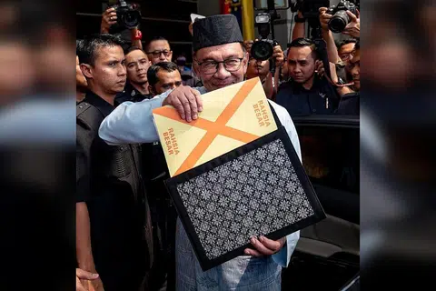 BENTANG BELANJAWAN: Datuk Seri Anwar yang berpakaian baju Melayu lengkap berwarna biru muda bersamping yang dihasilkan oleh Penjara Penor, Pahang dan bersongkok serta memakai capal dari Kepala Batas dilihat membawa beg fail warna hitam bermotif corak tenunan Sarawak yang berisi teks ucapan pembentangan Belanjawan 2023 sebelum meninggalkan Kementerian Kewangan ke Parlimen. - Foto FACEBOOK ANWAR IBRAHIM