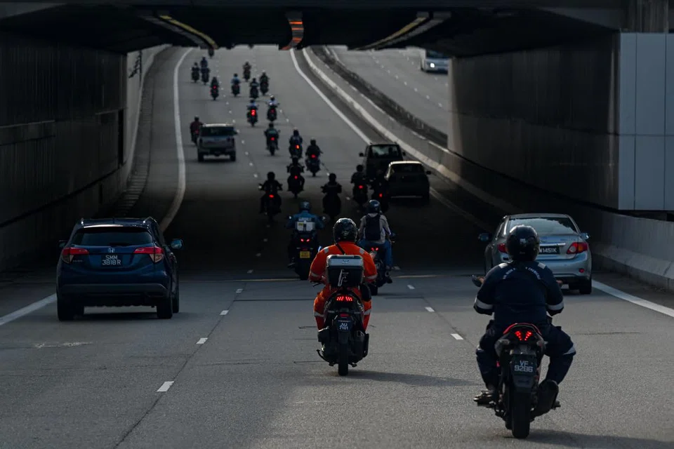 Warga Malaysia menunggang motosikal di jalan raya.