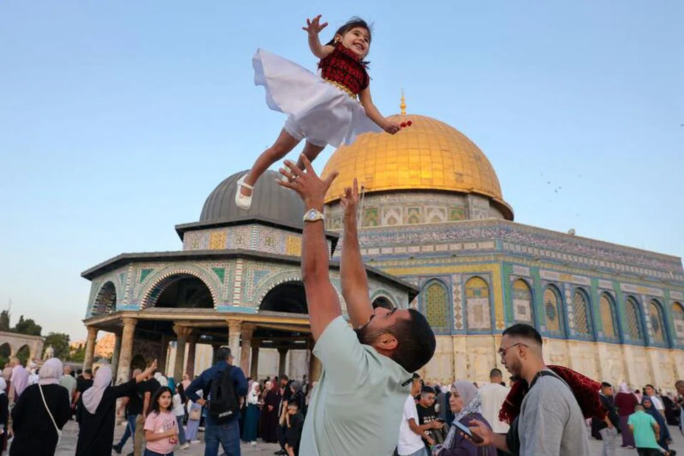 Seorang lelaki seronok menyambut Aidiladha bersama anak perempuannya dan jemaah lain semasa solat sunat Aidiladha di Kubah Al-Sakhrah dekat Masjid Al-Aqsa pada 6 Jun. 