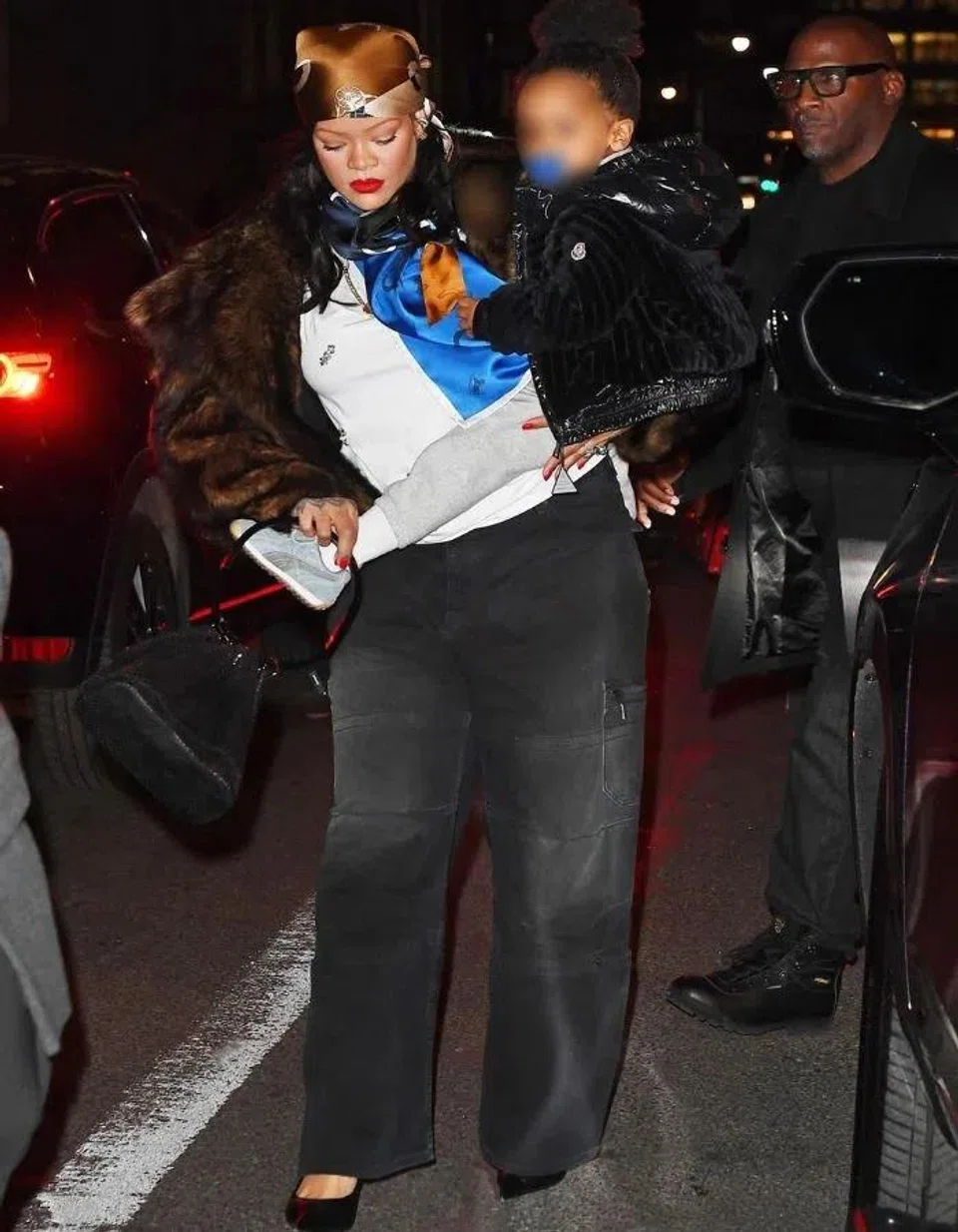 Penyanyi terkenal Rihanna menggayakan kemeja-T putih dengan skarf bercorak di kepala dan leher.