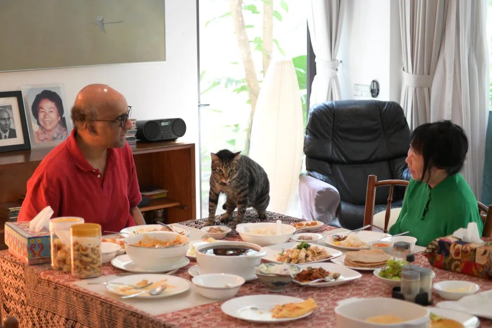 JAMU SELERA: Encik Tharman Shanmugaratnam meluangkan masanya pada Hari Bertenang bersama isterinya, Cik Jane Ittogi, di rumah dengan menikmati makanan kegemaran mereka iaitu nasi ayam dan capati bersama kuah kari. Salah satu daripada tiga kucing mereka, yang bernama Awan, menemani mereka di meja makan.