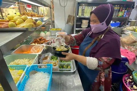 HARGA SEIMBANG: Cik Asih Nimang,48 tahun bersyukur pelanggan mereka faham dengan peningkatan harga makanan mereka. - Foto BH oleh RABIATUL ADAWIYA BINHAN