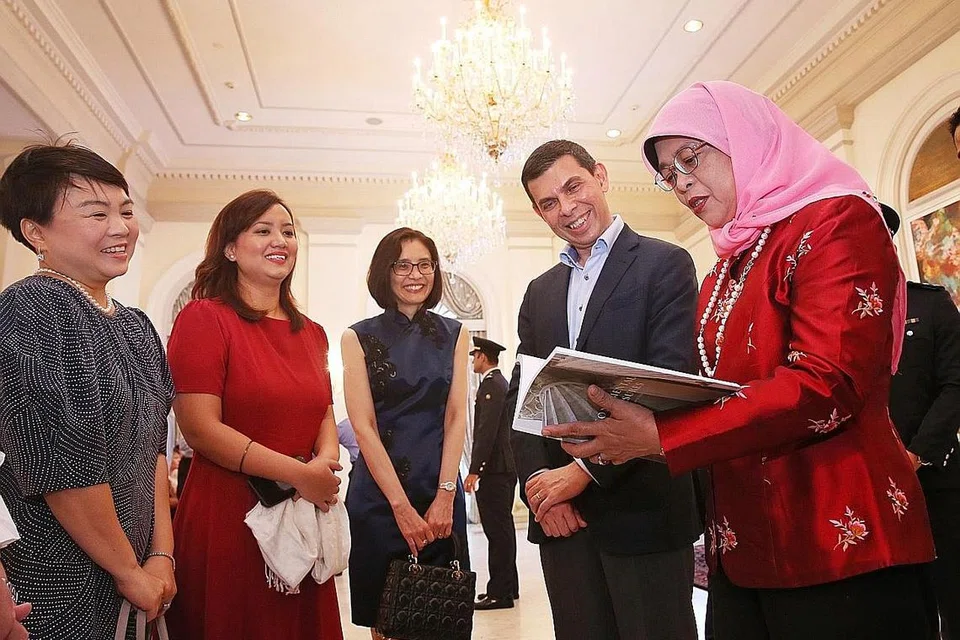 SEJARAH MONUMEN NEGARA: (dari kiri) Pengurus Besar Straits Times Press, Cik Susan Long; koresponden ST dan editor buku Monumental Treasures: Singapore's Heritage Icons, Cik Melody Zaccheus; CEO NHB, Cik Chang Hwee Nee; dan Encik Warren Fernandez sama-sama menyaksikan Presiden Halimah Yacob membaca buku Monumental Treasures: Singapore's Heritage Icons semasa majlis pelancaraannya di Istana semalam. - Foto BH oleh GAVIN FOO