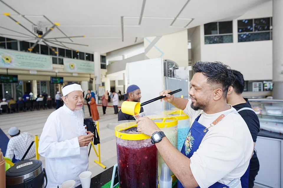 Pengasas Balang Kepalang, Encik Andy Idris (dua dari kanan), menyediakan minuman air balang untuk jemaah di Masjid Al-Ansar sebelum solat Jumaat bermula pada 13 September.