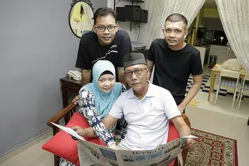 NOSTALGIA BACA BERITA: Muhammad Aidil (kiri, barisan kedua) bersama keluarganya, ibunya Cik Fatimah Zahid, bapanya Encik Zulkifli Muhammad Salleh, dan adiknya Muhammad Azfar Zulkifli, lebih gemar membaca surat khabar fizikal berbanding dengan versi digital. - Foto BM oleh AZMI ATHNI