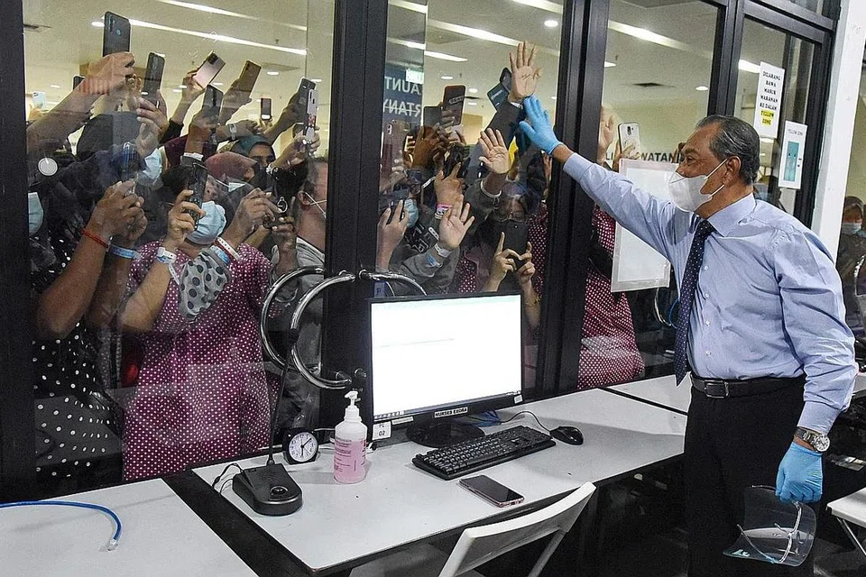 GOLONGAN POSITIF COVID-19: Perdana Menteri Malaysia, Tan Sri Muhyiddin Yassin melambaikan tangan kepada mereka yang positif Covid-19 di kemudahan kuarantin di Taman Pertanian Agro Malaysia di Serdang, luar Kuala Lumpur. - Foto AFP