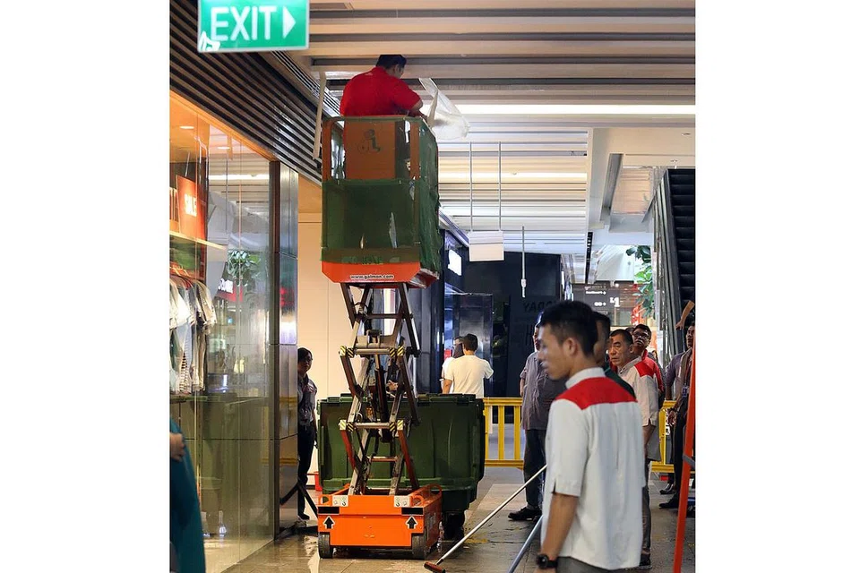 SEDANG DIBAIKI: Pekerja membetulkan dan membersihkan siling bocor di Jem. Kebocoran selama sekitar tiga jam sewaktu masa makan tengah hari semalam mengakibatkan beberapa kedai makan terjejas. - Foto ZAOBAO