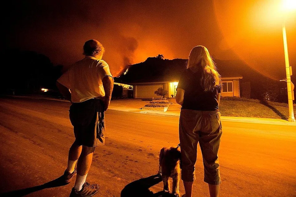 TERBAKAR DI HADAPAN MATA: Penduduk melihat sebuah rumah terbakar di kawasan berbukit di Monrovia, California, pada bulan lalu. Kebakaran hutan besar yang marak selama lebih seminggu telah turut mengancam keselamatan beberapa bangunan penting di situ termasuk menara untuk khidmat observatori dan penyiaran. - Foto AFP