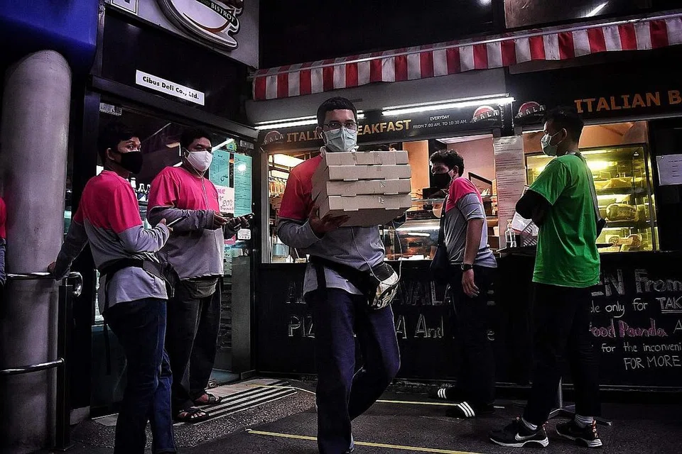 NIKMATI PENINGKATAN: Pekerja penghantar makanan sibuk mengambil tempahan pelanggan sebelum perintah berkurung dikuatkuasakan di Bangkok pada awal April lalu. Khidmat e-perniagaan dan penghantaran makanan mengalami peningkatan di tengah-tengah pandemik Covid-19. - Foto AFP