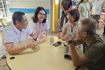 Menteri di Pejabat Perdana Menteri, Dr Mohamad Maliki Osman (kiri) memperkenalkan muka baru Parti Tindakan Rakyat (PAP), Cik Hazlina Abdul Halim (dua dari kiri), kepada penduduk di Pasar Fengshan di Bedok pada 12 April.