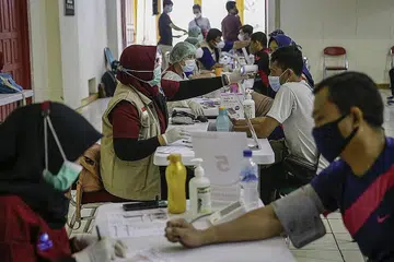 BERSIAP DAPATKAN VAKSIN: Pekerja sektor runcit di sekitar Jakarta menjalani pemeriksaan kesihatan sebelum diberikan vaksin AstraZeneca dalam usaha membendung penularan jangkitan Covid-19. - Foto EPA-EFE