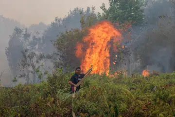 Seorang anggota bomba memadamkan kebakaran di kampung Sungai Tabuk di Kabupaten Banjar, Kalimantan Selatan, pada 16 Oktober.