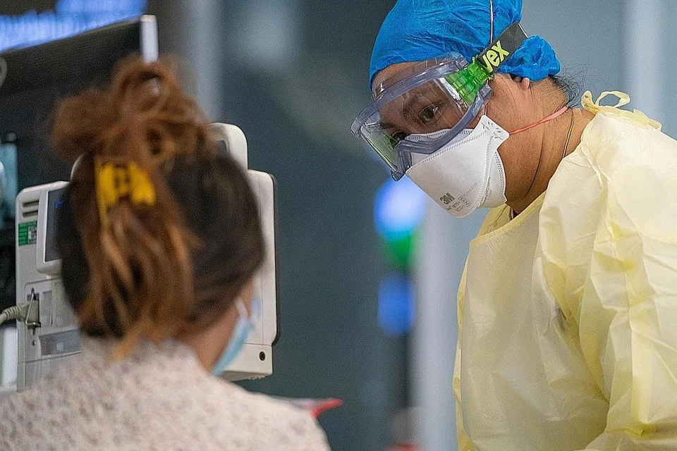 BANTU PESAKIT: Cik Noor Juliana Abdul Rahman lengkap dengan peralatan perlindungan peribadi, pelitup N95 dan gogal membantu seorang pesakit di Hospital Besar Ng Teng Fong. - Foto HOSPITAL BESAR NG TENG FONG