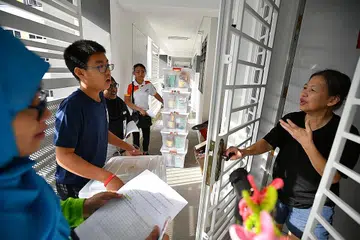 KERJASAMA BANTU YANG MEMERLUKAN: Sukarelawan dari pelbagai latar belakang dan juga agama berkumpul untuk mengagihkan makanan kepada penduduk yang memerlukan di kawasan Punggol dalam aktiviti yang dianjurkan bersama Masjid Al-Islah, Punggol West IRCC, Kuil Darmakaya dan Church of the Transfiguration Sabtu lalu. - Foto BH oleh LIM YAOHUI