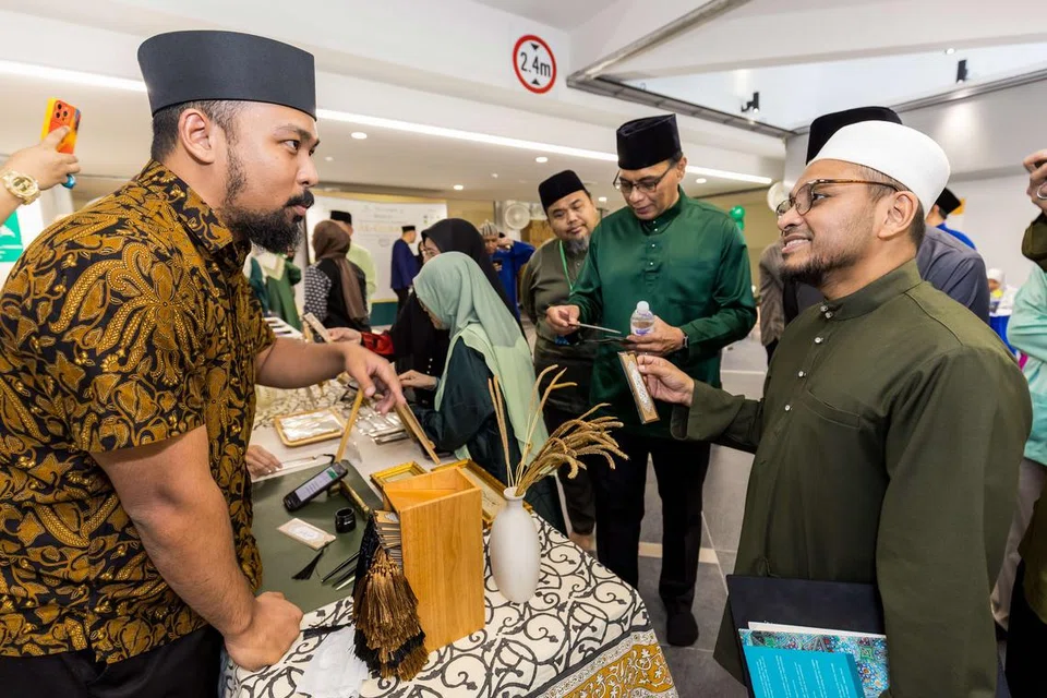 Mufti Singapura, Dr Nazirudin Mohd Nasir (kanan), berinteraksi dengan artis kaligrafi bahasa Arab, Ustaz Ammar Mustafa, sempena acara perayaan keluarga QuranSG 2025 di Masjid Darul Makmur pada 26 Julai.