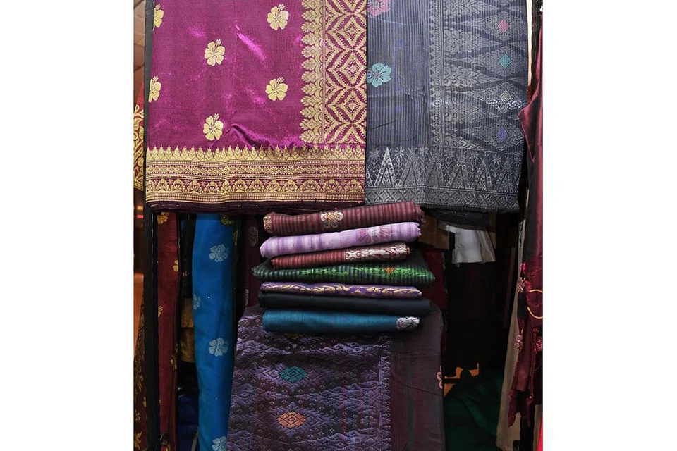 BERANEKA WARNA DAN REKA CORAK: Kain songket dalam pasaran sekarang berwarna terang dan berkilauan malah boleh disesuaikan mengikut cita rasa pelanggan. Dalam gambar ini, antara songket yang dipaparkan ialah songket bunga tabur menggunakan motif bunga raya (kain sebelah kiri yang berwarna ungu muda). Bunga raya melambangkan kekuatan serta keharmonian dalam kepelbagaian. Turut dipaparkan ialah kain songket bermotif pucuk rebung berjuang pada bahagian kepala (kain bahagian bawah gambar berwarna ungu tua).- Foto BM oleh KHALID BABA