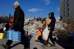 MANGSA GEMPA: Orang ramai membawa botol air dan kotak berisi roti selepas gempa di bandar Kahramanmaras, Turkey. - Foto REUTERS