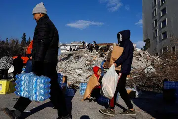 MANGSA GEMPA: Orang ramai membawa botol air dan kotak berisi roti selepas gempa di bandar Kahramanmaras, Turkey. - Foto REUTERS