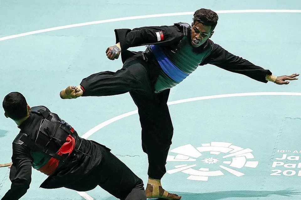 PENCAPAIAN BAIK: Pesilat negara Sheik Ferdous Sheik Alau'ddin (kanan) cuba menendang lawannya Aji Bangkit Pamungkas dari Indonesia di final acara silat Kelas I (85-90)kg. Sheik Ferdous tewas 0-5 kepada pesilat dari pasukan tuan rumah, tetapi beliau mencatat sejarah sebagai pemenang pingat perak acara tanding pertama negara di Sukan Asia. - Foto SNOC