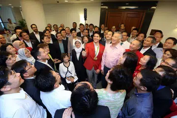 Joseph Schooling (memegang kamera) bergambar bersama Encik Lee (sebelah kirinya) serta para menteri dan anggota parlimen (AP) lain di bangunan Parlimen pada 2016.