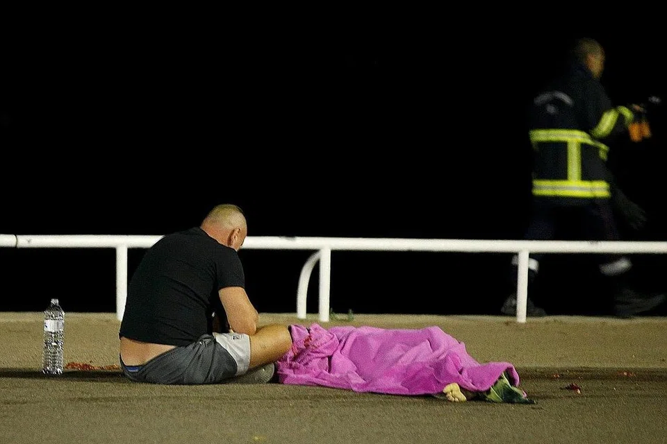 RATAPI PEMERGIAN: Lelaki ini duduk di sebelah mayat yang terkorban dalam serangan berdarah di Nice kelmarin. - Foto REUTERS 
