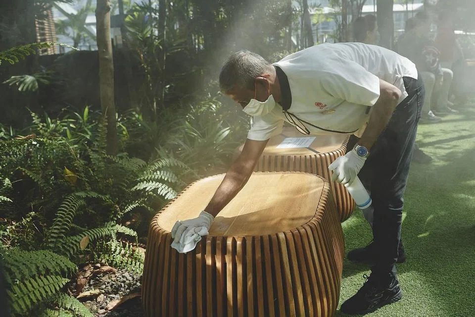 PASTIKAN BERSIH: Seorang pekerja pembersihan disinfektasi tempat duduk di Foggy Bowls di Canopy Park. -Foto TED CHEN, JEWEL CHANGI AIRPORT