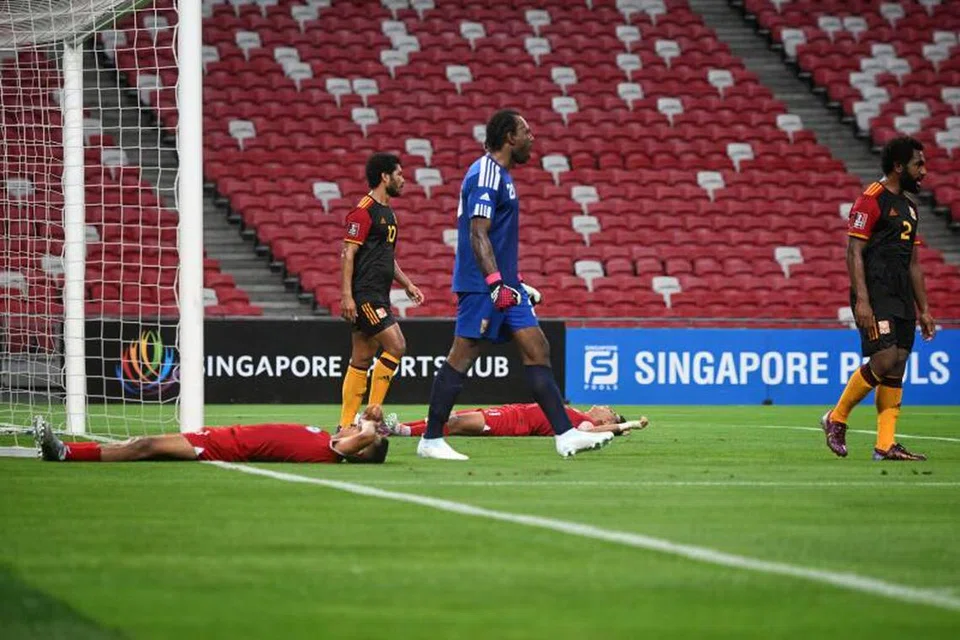KECEWA: Pemain Singapura (jersi merah) terdampar di padang selepas satu lagi peluang gol disesiakan dalam perlawanan persahabatan menentang Papua New Guinea  di Stadium Negara pada 16 Jun. 