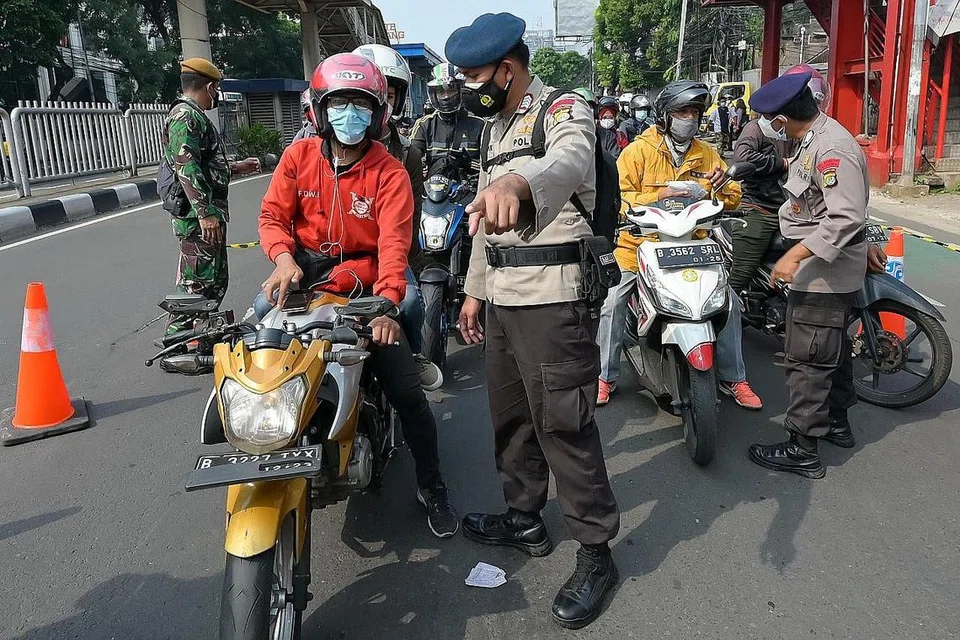 JALANI PEMERIKSAAN: Pegawai polis dan tentera menjalankan pemeriksaan bagi mengawal pergerakan manusia bagi membendung penularan Covid-19 di Indonesia. - Foto AFP