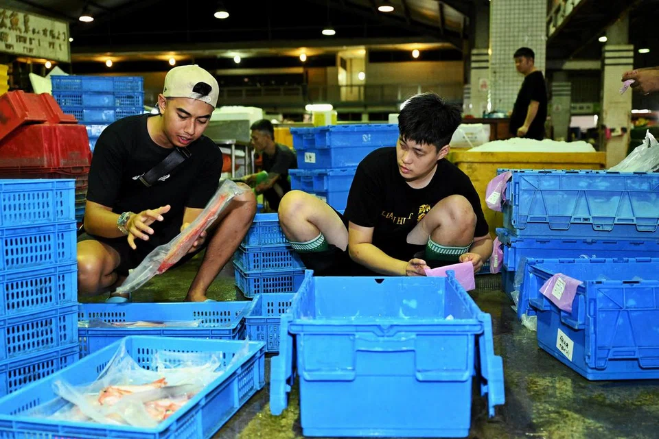 SUDAH TIGA TAHUN: Encik Muhammad Mizzuan Maslan akui masih setahun jagung dalam bidang ini. Beliau digambar bersama salah seorang kakitangan yang membantunya di Pelabuhan Perikanan Jurong. 