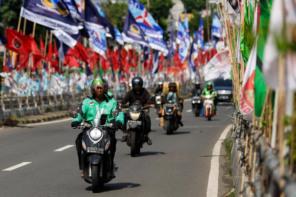 DIPANTAU: Para pengguna jalan raya melepasi bendera parti politik yang dipasang di sepanjang jalan, menjelang pilihan raya umum di Jakarta, Indonesia, sedang Pusat Laporan dan Analisis Transaksi Kewangan (PPATK) mendapati dana asing dilapor membiayai parti setempat.