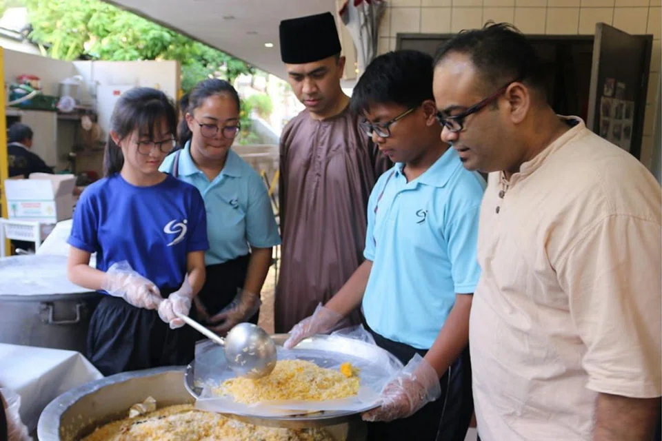PUPUK HARMONI: Pelajar Elis Ong dari Sekolah Menengah Riverside (kiri) bersama rakan membantu menyiapkan juadah buka puasa di Masjid Darul Makmur Jumaat lalu. Mereka ditemani pengurus masjid tersebut, Ustaz Ruhaizan Abdullah (bersongkok), dan guru Sekolah Menengah Riverside, Encik Muhammad Hafiz Said (kanan). - Foto ihsan NUR INDAH MD YUSOFF
