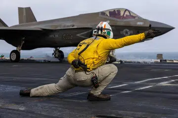 Seorang anggota Tentera Laut Amerika Syarikat memberi isyarat bagi pelancaran pesawat pejuang F-35C Lightning II dari dek kapal induk USS Abraham Lincoln ketika konflik dengan Iran, pada 5 Ogos 2026. Amerika kini menggerakkan kapal induk USS George Washington ke Timur Tengah untuk menggantikan USS Abraham Lincoln, yang sudah berada di laut lebih 240 hari tanpa henti, susulan laporan mengenai masalah bekalan dan tekanan terhadap kesihatan mental anak kapalnya