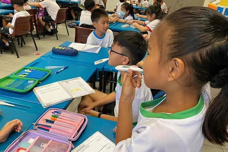 LANGKAH BERJAGA-JAGA: Murid Sekolah Rendah Westwood mengambil suhu mereka pada hari pertama sekolah dibuka semalam selepas cuti Tahun Baru Cina. - Foto SEKOLAH RENDAH WESTWOOD