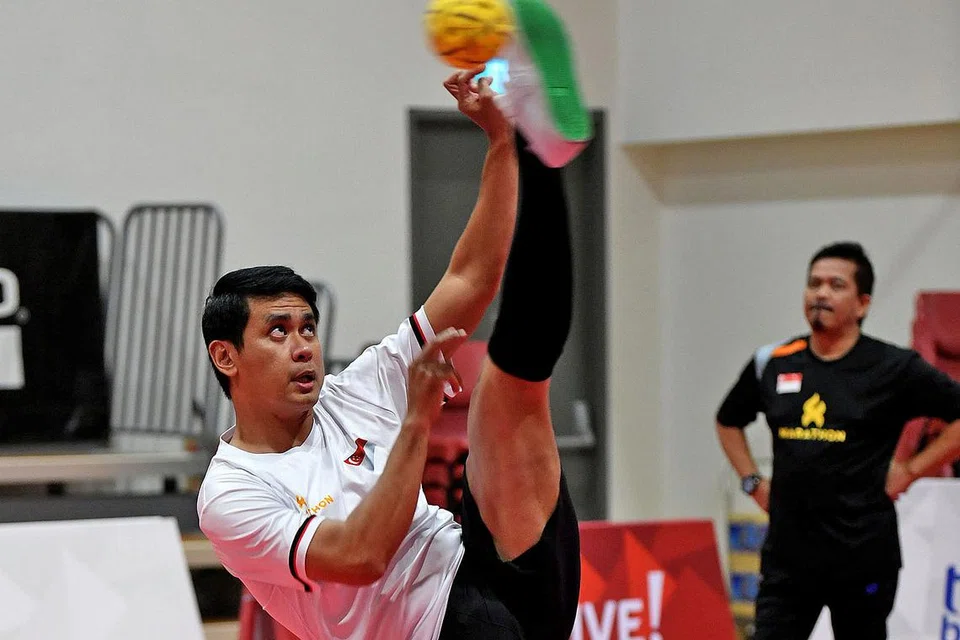 YAKIN CAPAI KEJAYAAN: Farhan (depan) menyepak bola takraw sambil disaksikan oleh jurulatih Salleh (belakang) semasa latihan pasukan sepak takraw nasional di Dewan Sepak Takraw di Heartbeat @ Bedok pada Rabu lalu. - Foto BH oleh KHALID BABA