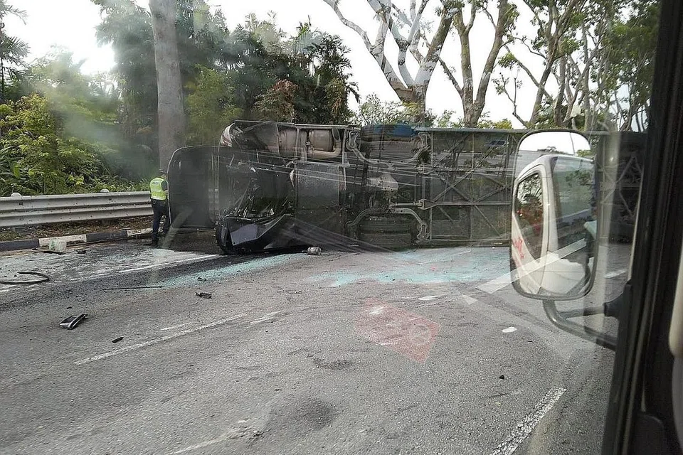KESAN KEMALANGAN: Bas yang terlibat dalam kemalangan di Pulau Jurong itu terbalik di sisinya, sementara bahagian depan kereta itu pula mengalami kerosakan teruk. - Foto ihsan PEMBACA ST