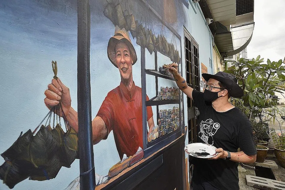 MELUKIS: Encik Alvin Mark Tan, seorang pelukis minyak tradisional dan juga pelukis moden, memberikan sentuhan akhir pada mural sebuah Penjaja Nonya Kueh Chang di lorong belakang Rumah Antik Katong. - Foto BH oleh DESMOND WEE 