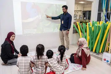 TEKNOLOGI: Encik Thariq sedang menunjukkan cara menggunakan projektor sentuh yang kini sudah mula digunakan dalam bilik darjah di PPIS Bukit Batok. Turut berinteraksi dengan kanak-kanak dan guru adalah Cik Anizah (paling kiri). - Foto BM oleh NUR DIYANA TAHA