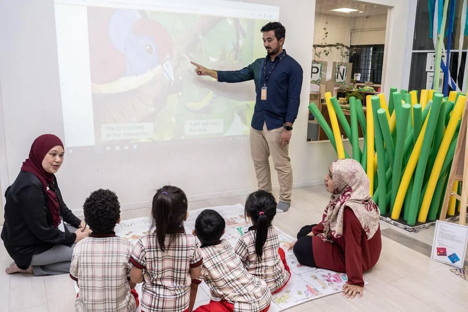 TEKNOLOGI: Encik Thariq sedang menunjukkan cara menggunakan projektor sentuh yang kini sudah mula digunakan dalam bilik darjah di PPIS Bukit Batok. Turut berinteraksi dengan kanak-kanak dan guru adalah Cik Anizah (paling kiri). - Foto BM oleh NUR DIYANA TAHA